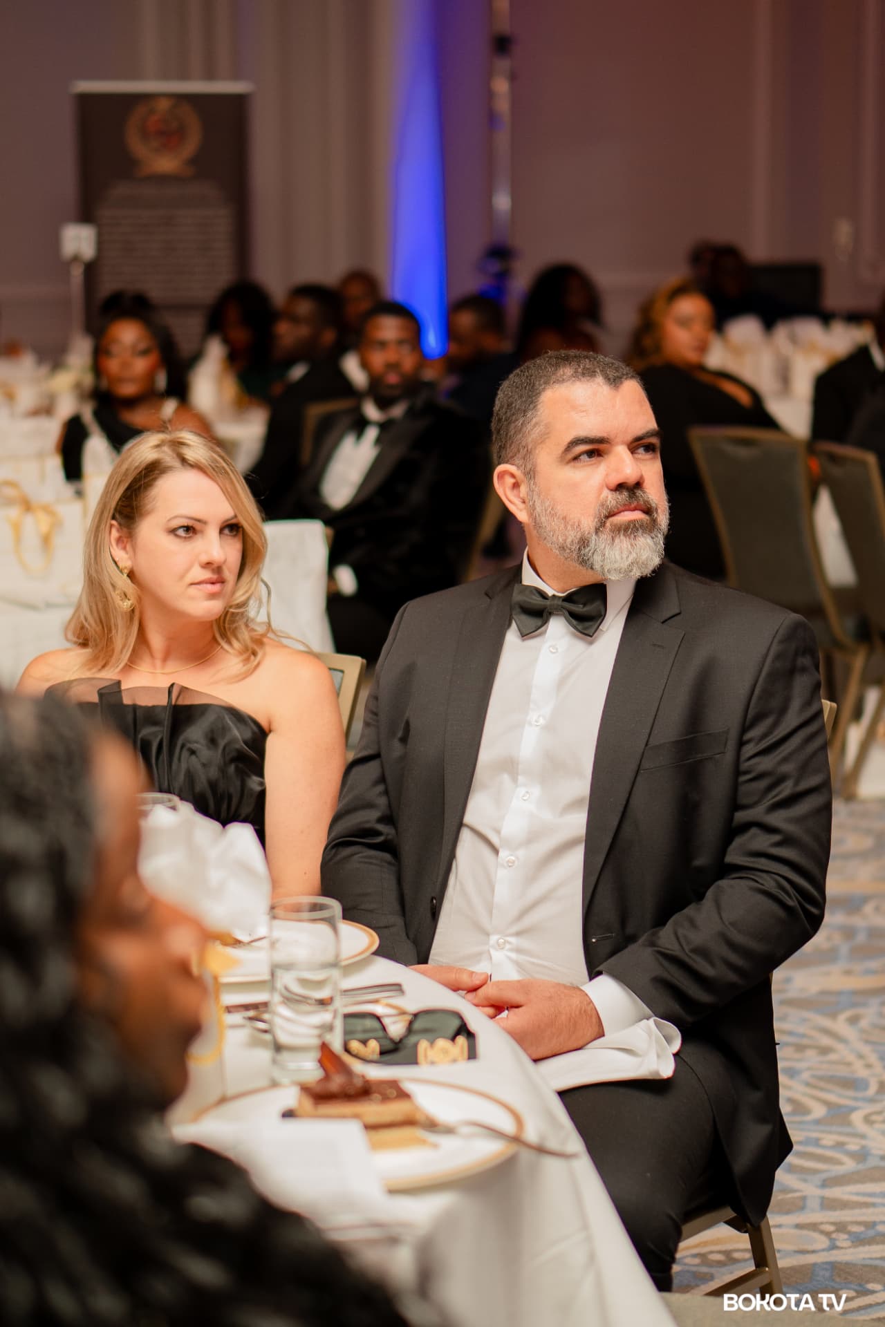 Two guests in evening dress listen attentively at their table during the gala programme
