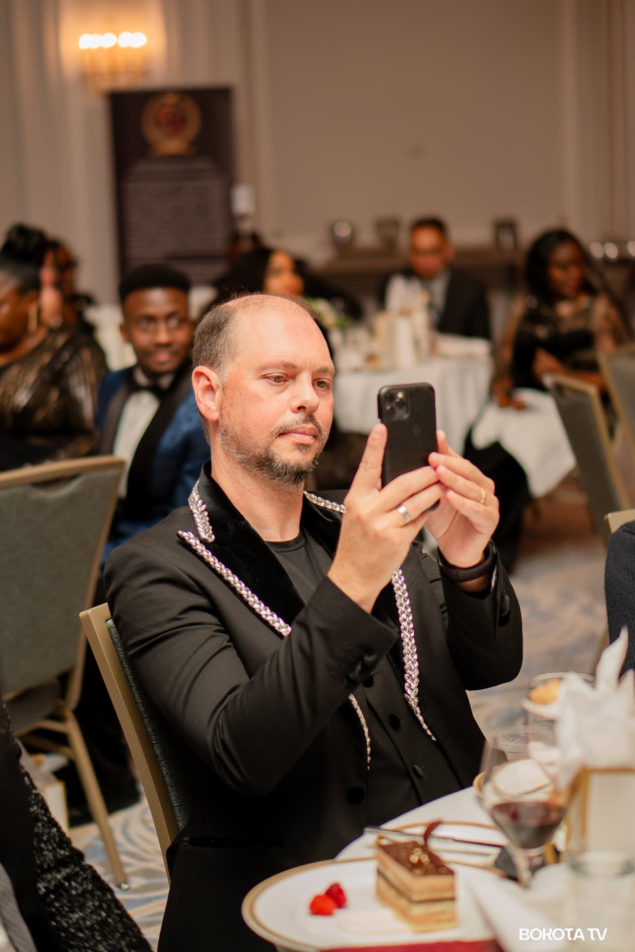 A guest photographs the stage on his phone during MBOMBO Gala Night