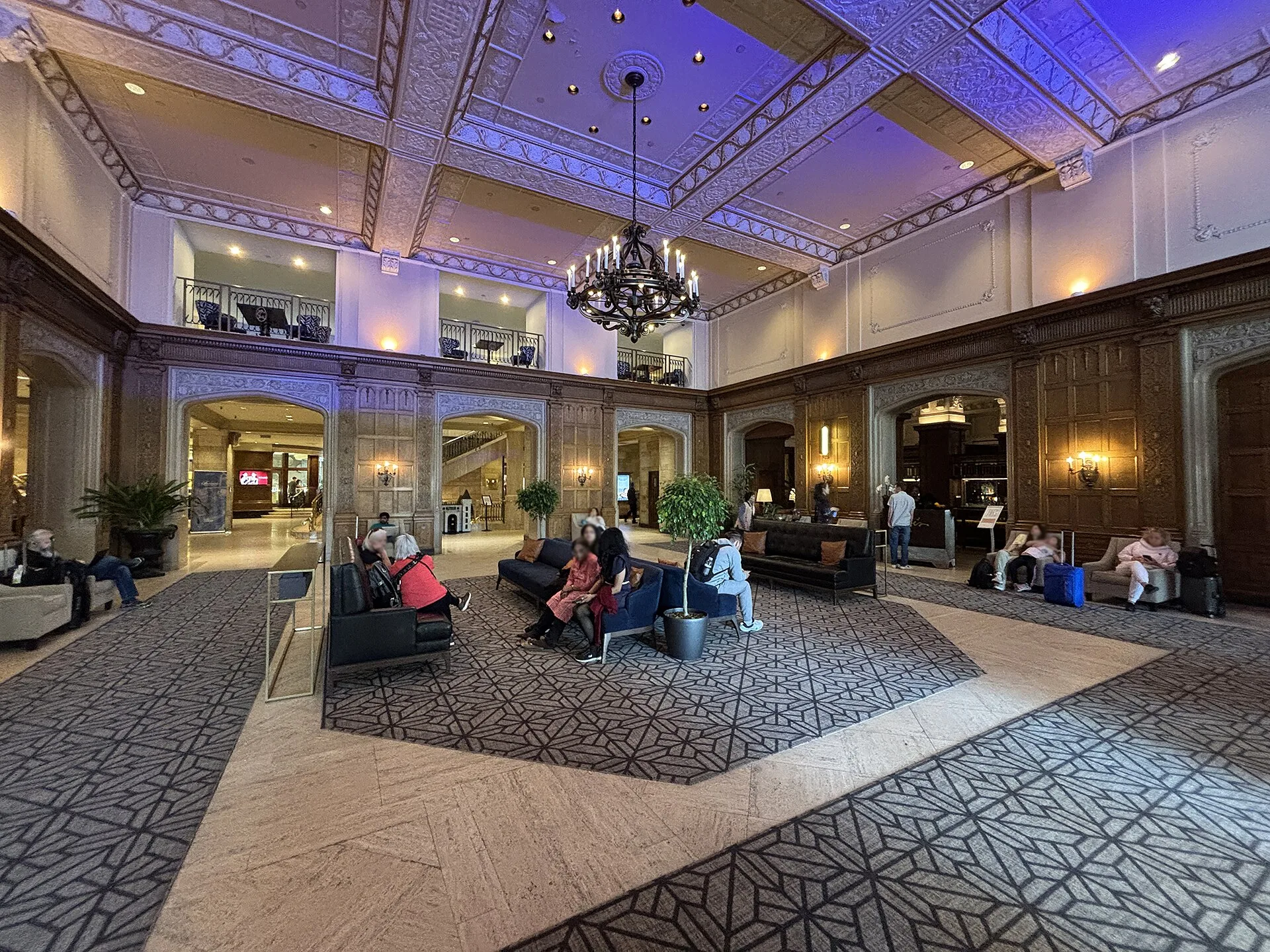 The panelled lobby of the Fairmont Château Laurier in the evening, lit by a wrought-iron chandelier
